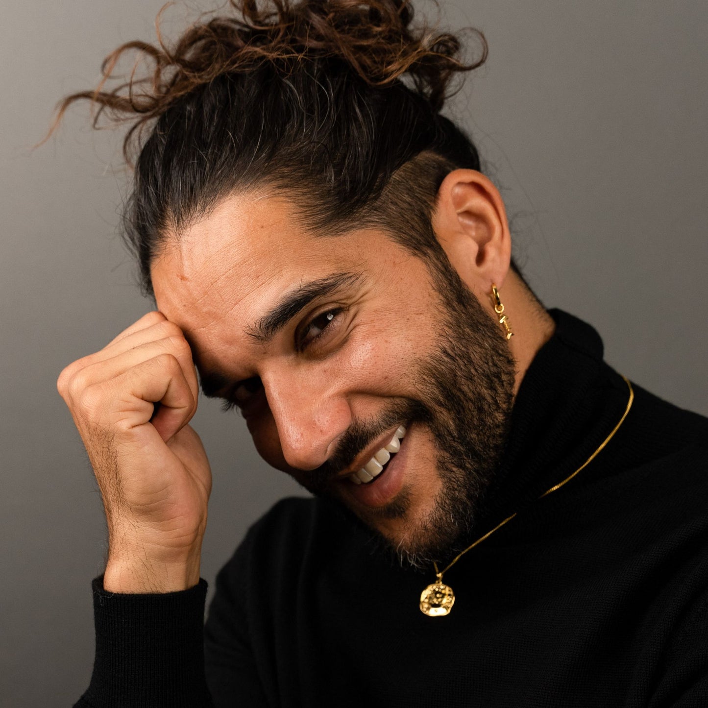 male model wearing the lars cat coin necklace in 18k gold vermeil and the mars fish bone huggie hoop earring in 18k gold vermeil