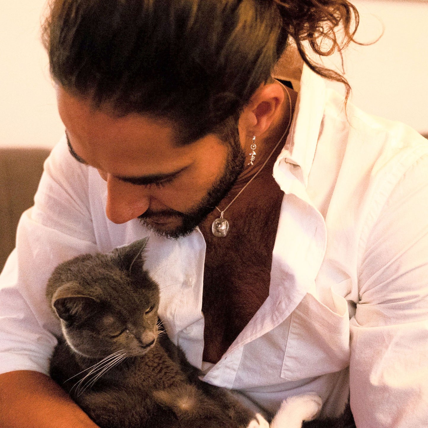 male model wearing the lars reversible cat coin necklace in sterling silver and the mars fish bone huggie hoop earring