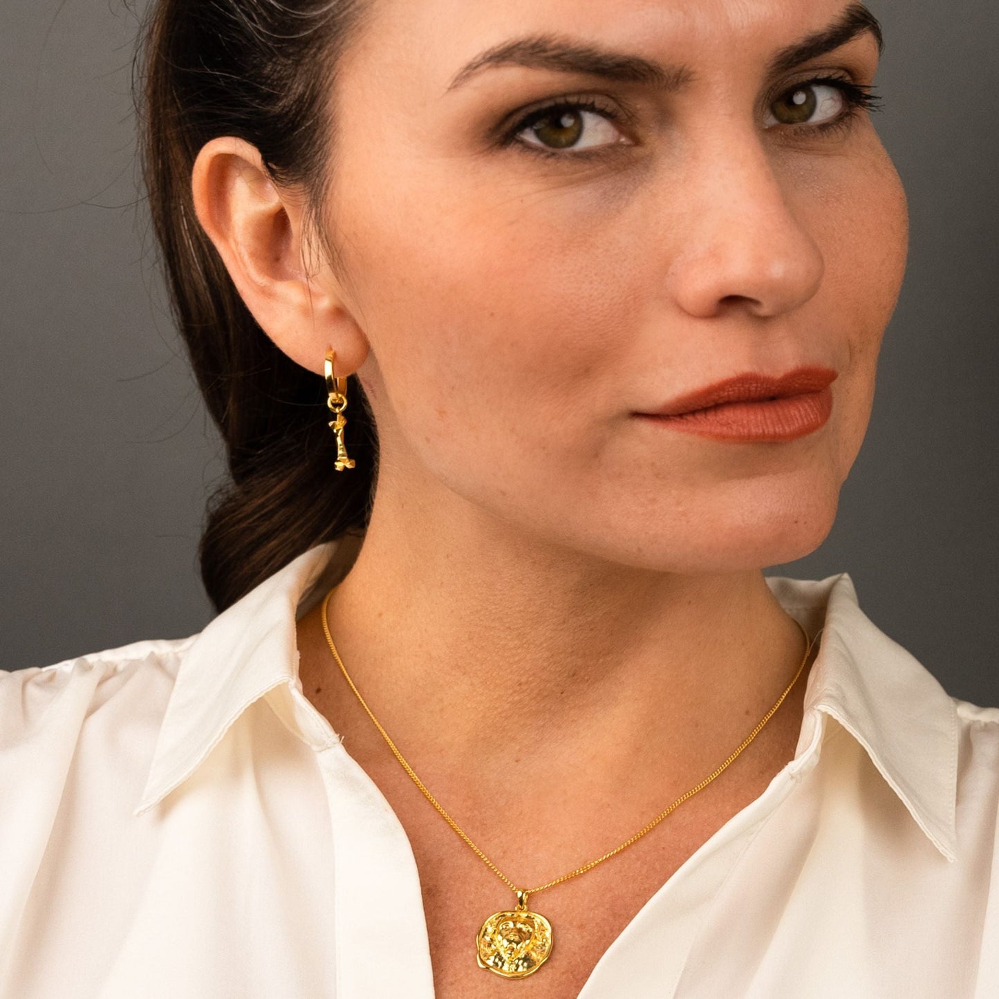 female model wearing the mars dog bone huggie hoop earring in 18k gold vermeil and the lars dog coin necklace in 18k gold vermeil