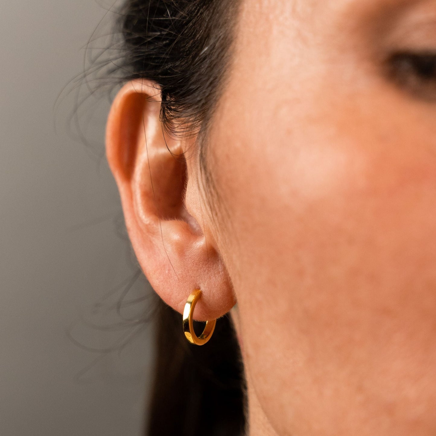 female model wearing the mars dog bone huggie hoop earring in 18k gold vermeil without the removable dog bone charm