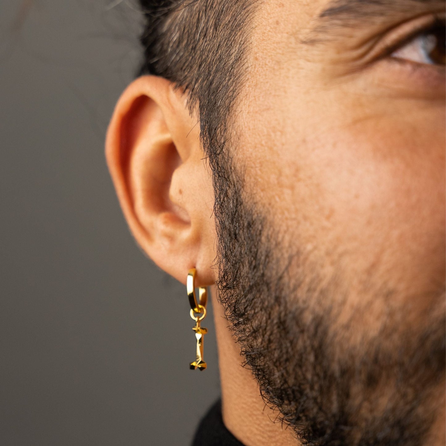 male model wearing the mars dog bone huggie hoop earring in 18k gold vermeil