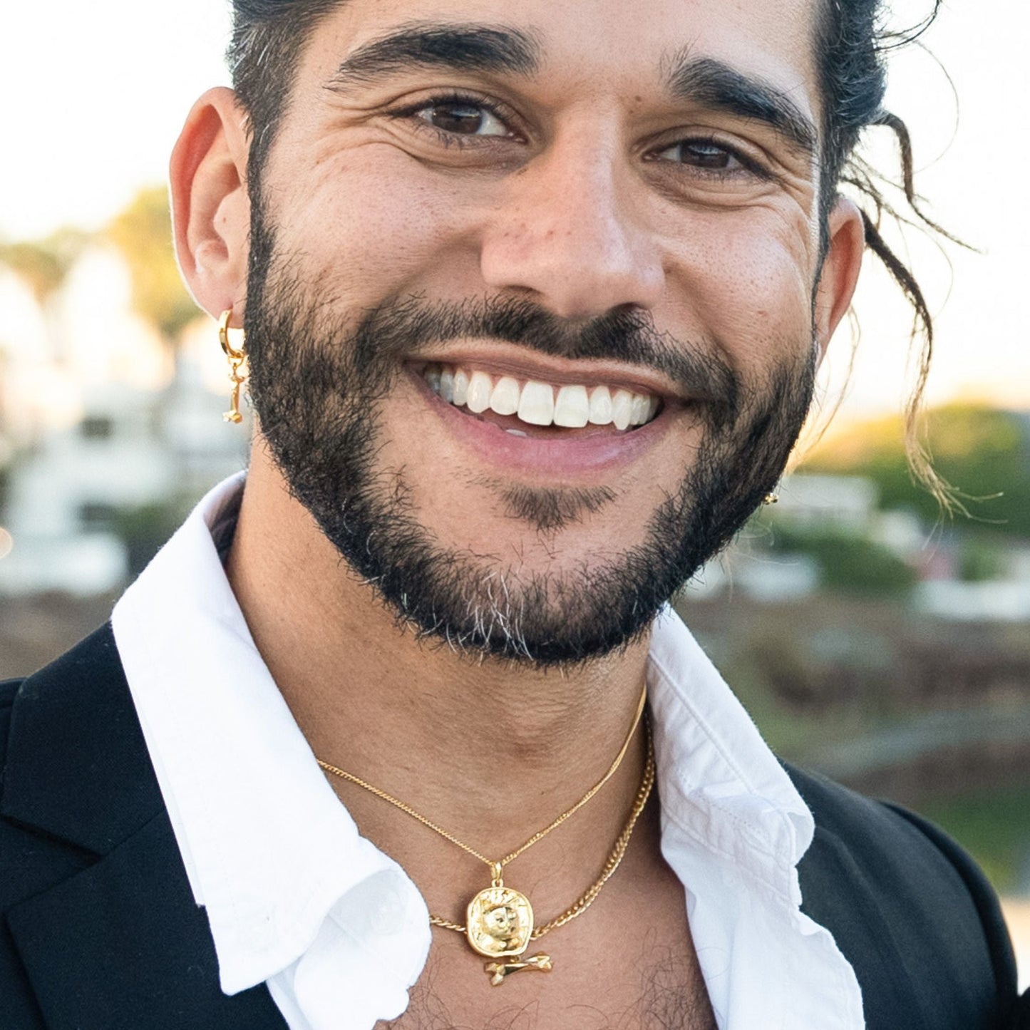 male model wearing the mars dog bone huggie hoop earring in 18k gold vermeil, the lars cat coin necklace in 18k gold vermeil and the mars dog bone necklace in 18k gold vermeil