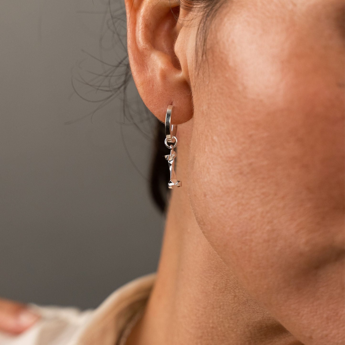 female model wearing the mars dog bone huggie hoop earring in sterling silver