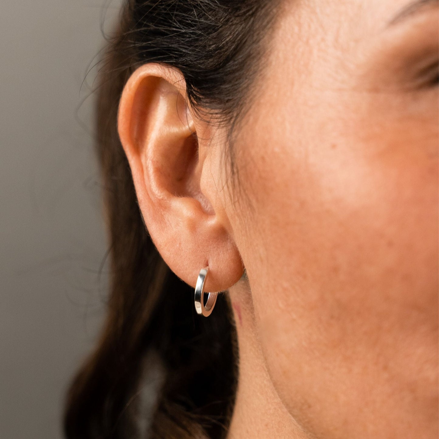 female model wearing the mars dog bone huggie hoop earring in sterling silver without the removable dog bone charm
