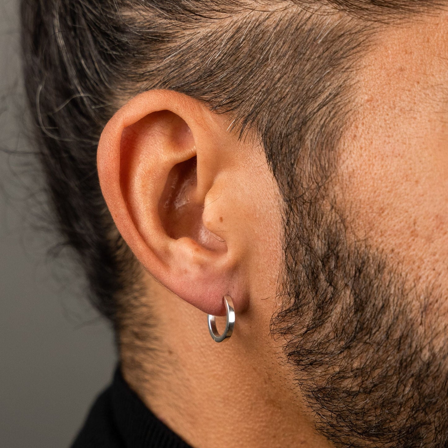male model wearing the mars dog bone huggie hoop earring in sterling silver without the removable dog bone charm