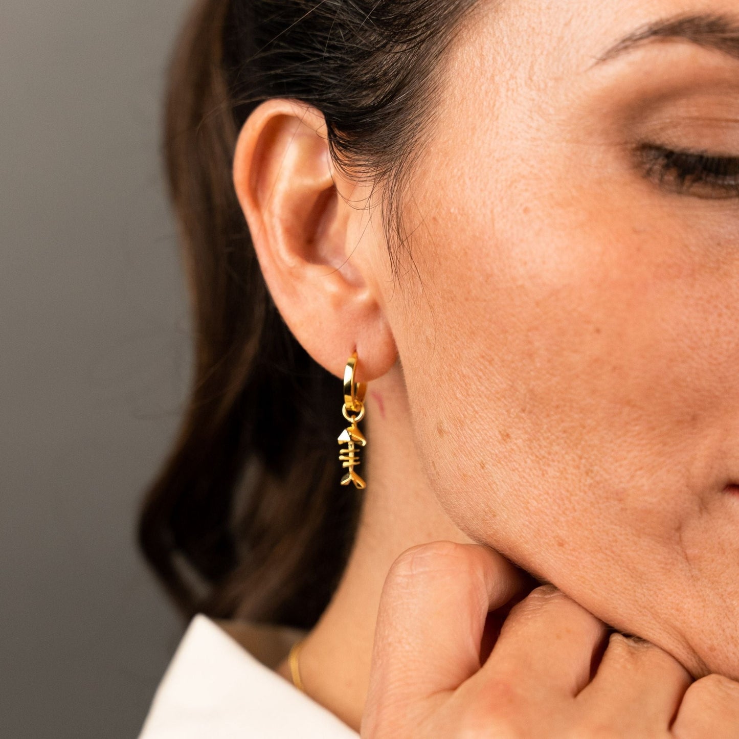 female model wearing the mars fish bone huggie hoop earring in 18k gold vermeil