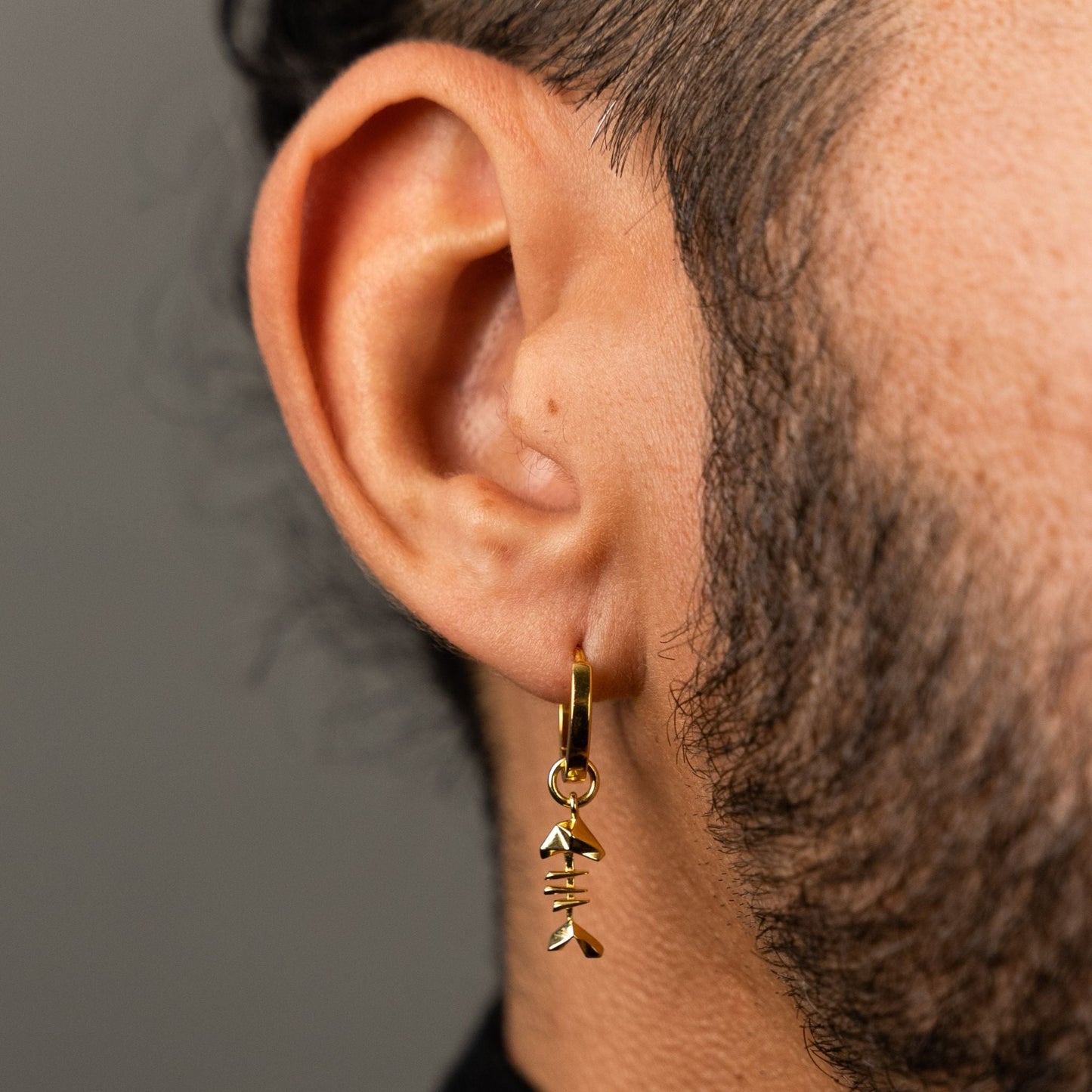 male model wearing the mars fish bone huggie hoop earring in 18k gold vermeil