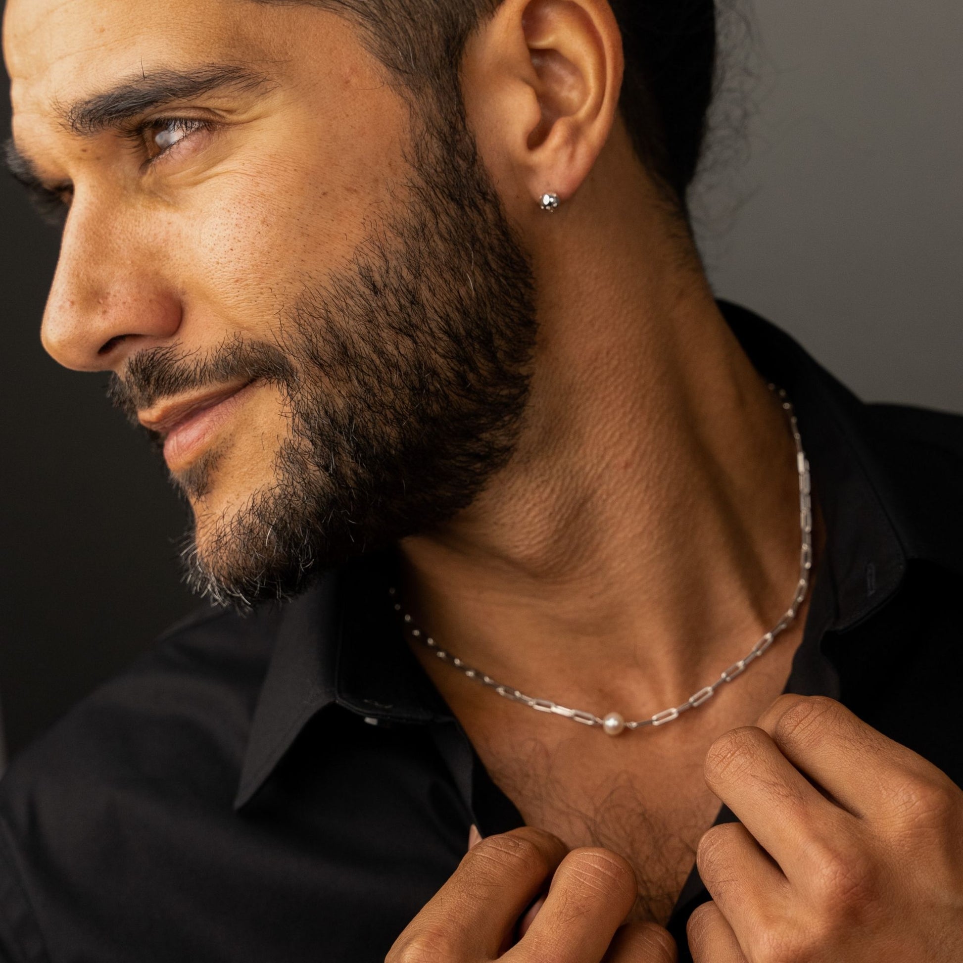 male model wearing the em mini paper clip pearl necklace in sterling silver and the fran ball stud earring in sterling silver
