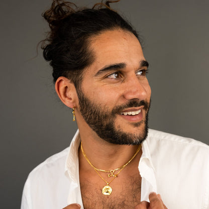 male model wearing the lars cat coin necklace in 18k gold vermeil, the mars dog bone necklace in 18k gold vermeil and the mars dog bone huggie hoop earring in 18k gold vermeil