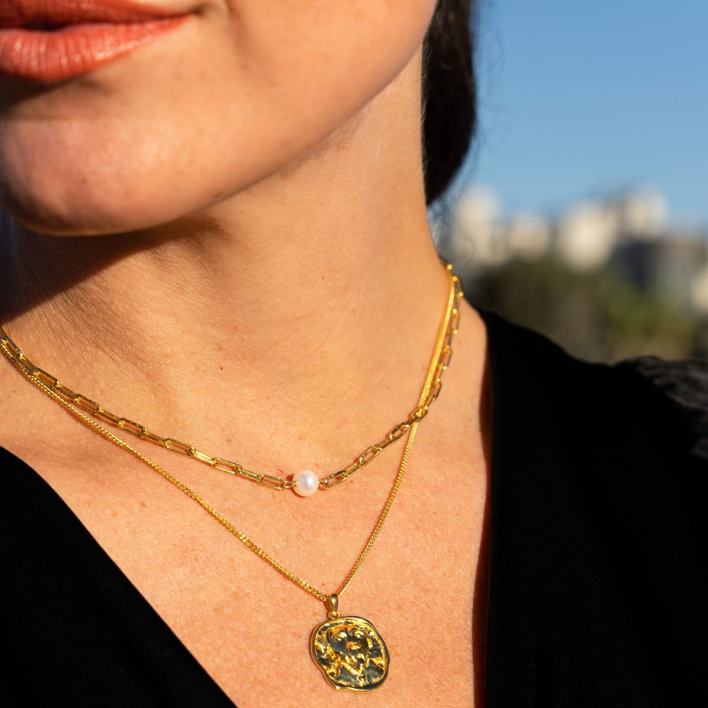 female model wearing the lars dog coin necklace in 18k gold vermeil and the em mini paper clip pearl necklace in 18k gold vermeil