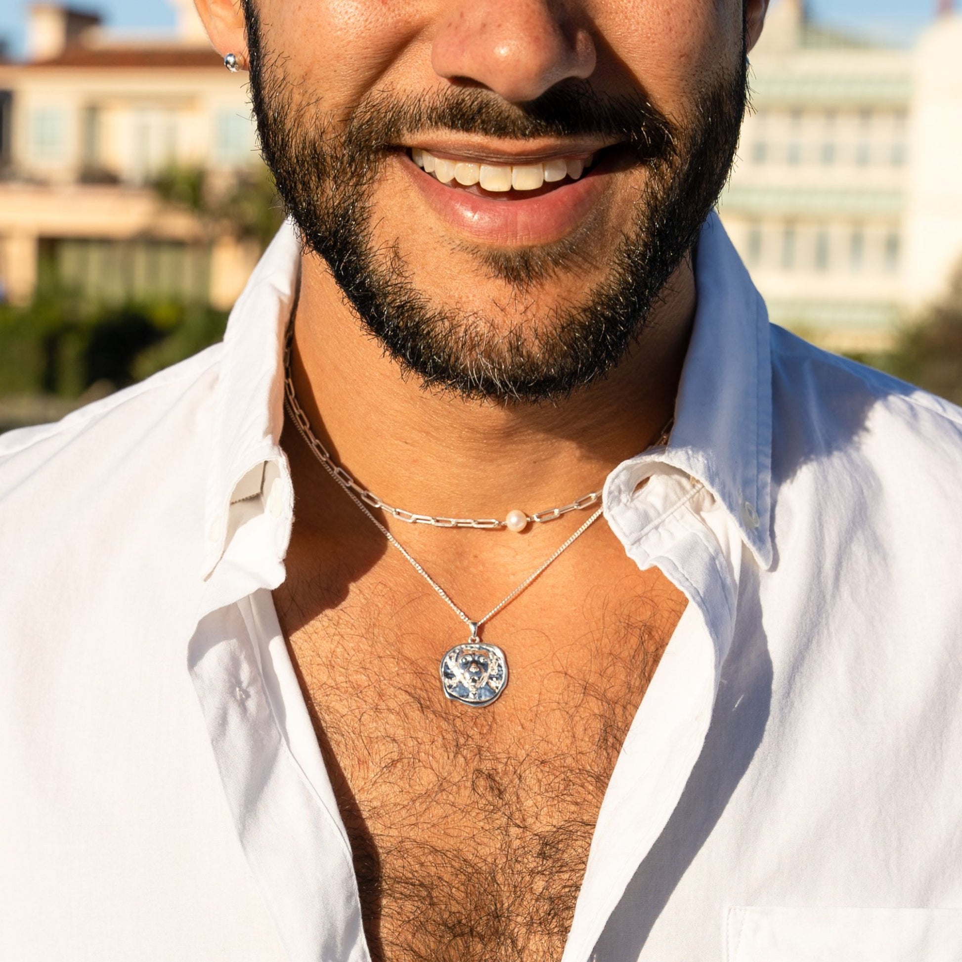 male model wearing the lars dog coin necklace in sterling silver, the em mini paper clip pearl necklace in sterling silver and the fran ball stud earring in sterling silver