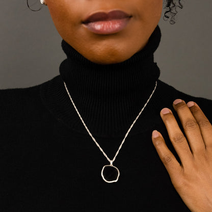 female model wearing the lars reversible dog coin necklace in sterling silver reversed, silver sheen obsidian, and the ren yarn stud earrings in sterling silver