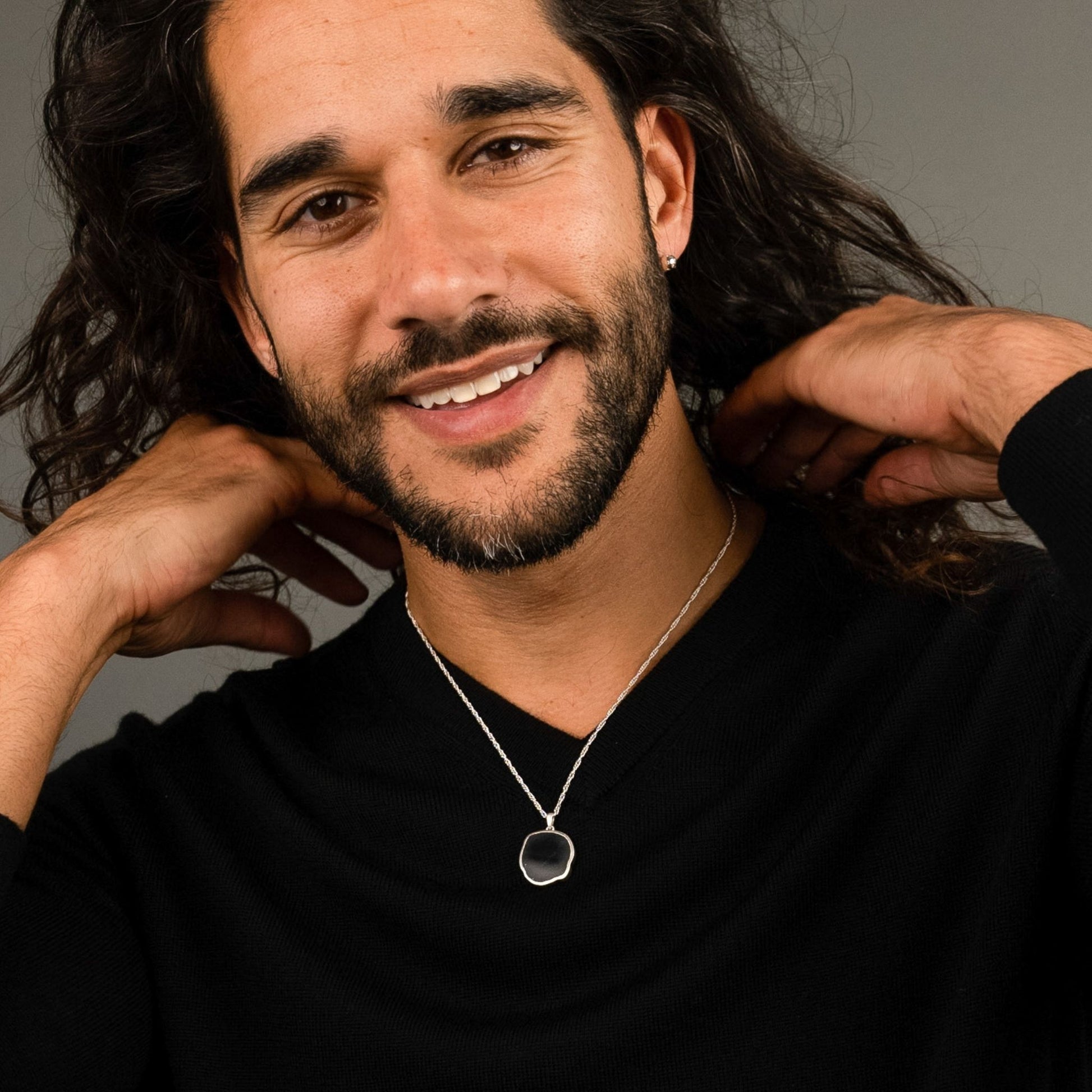 male model wearing the lars reversible dog coin necklace in sterling silver reversed, silver sheen obsidian, and the fran ball stud earring in sterling silver