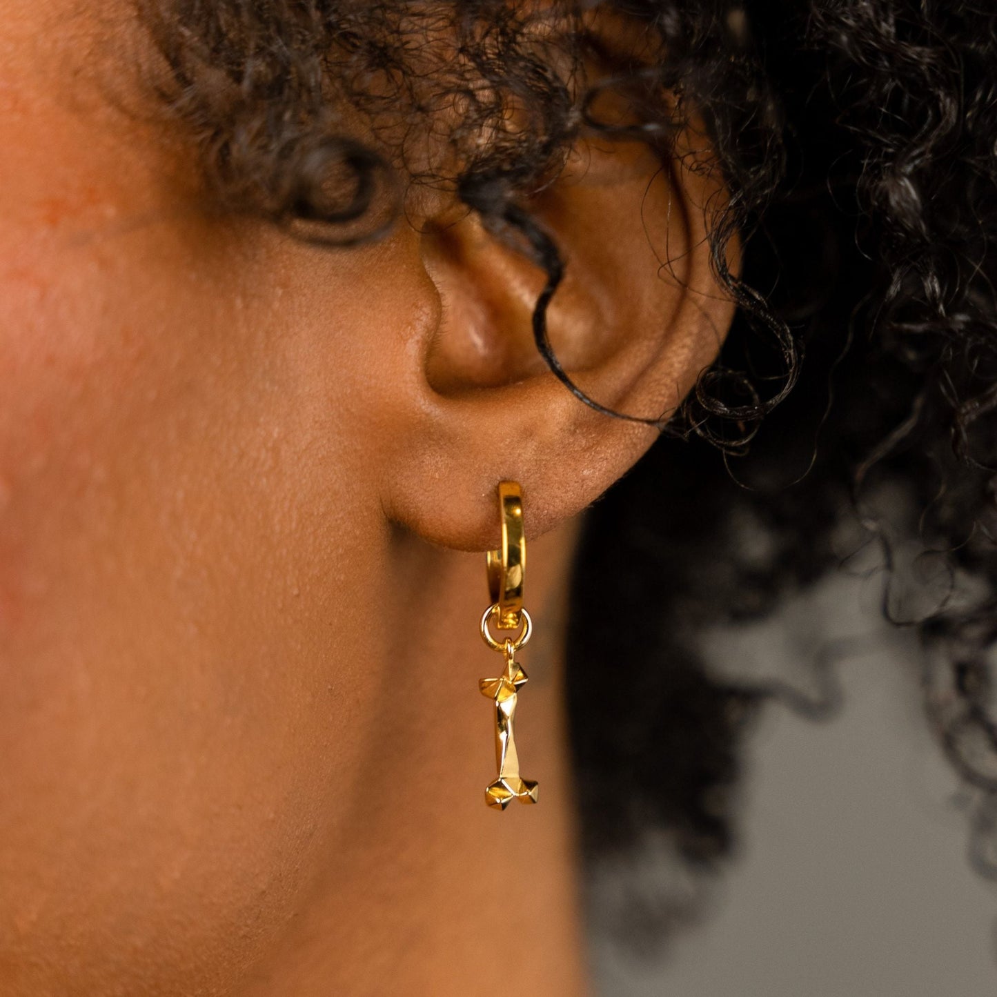 female model wearing the mars dog bone huggie hoop earring in 18k gold vermeil